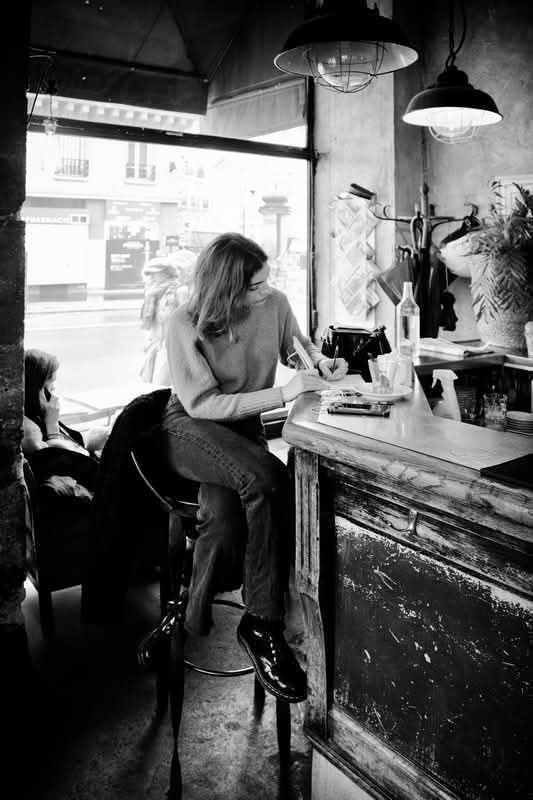 Mujer sola en un café, absorta, en blanco y negro